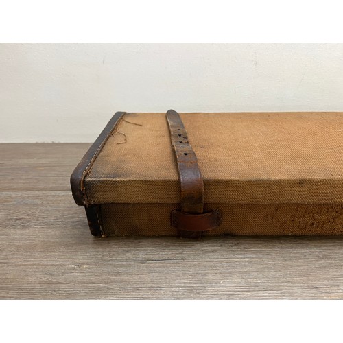 767 - A vintage canvas and leather shotgun case with baize lined interior compartments and oak and brass b... 