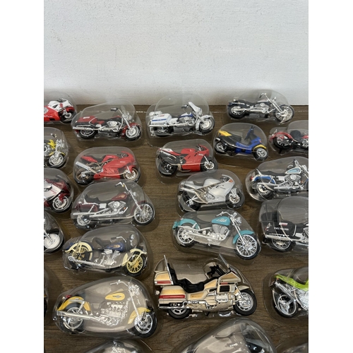 302 - A collection of packaged die-cast model motorcycles to include Harley Davidson, Yamaha, Police, Kawa... 