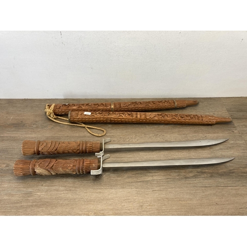 790 - A pair of Middle Eastern decorative tourist swords with carved hardwood handles and sheaths