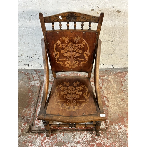 134 - An early 20th century beech rocking chair with embossed floral design