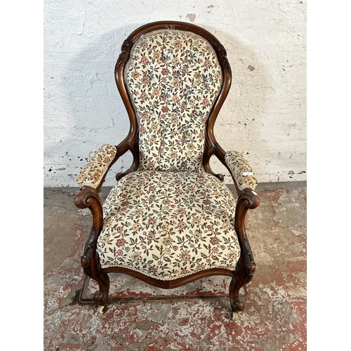 65 - A Victorian carved mahogany spoon back floral upholstered armchair on ceramic castors