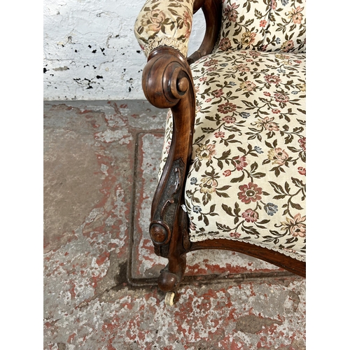 65 - A Victorian carved mahogany spoon back floral upholstered armchair on ceramic castors