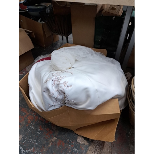 1130 - Three boxes containing wickerware, glassware, ceramics, wedding dress etc.