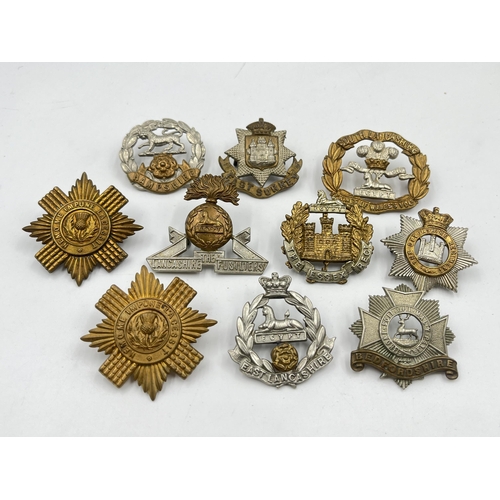 2101 - Ten military cap badges to include Bedfordshire, East Surrey, Lancashire Fusiliers etc.