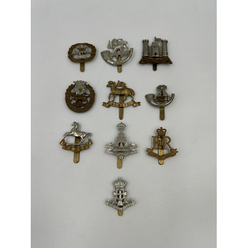 2174 - A collection of military cap badges