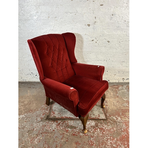 132 - A red fabric upholstered wing back armchair on cabriole supports