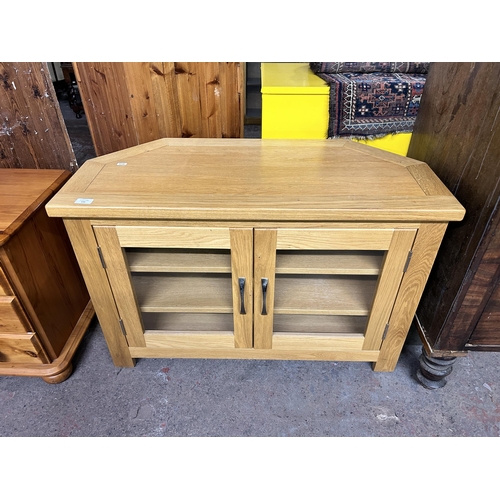 144 - A modern oak TV stand with two glazed doors - approx. 62cm high x 93cm wide x 43cm deep