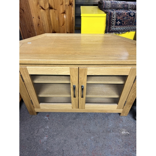 144 - A modern oak TV stand with two glazed doors - approx. 62cm high x 93cm wide x 43cm deep