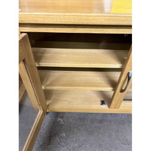 144 - A modern oak TV stand with two glazed doors - approx. 62cm high x 93cm wide x 43cm deep