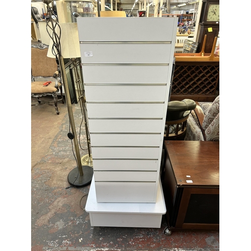 162 - A modern white laminate revolving slatwall display tower - approx. 152cm high