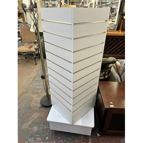 162 - A modern white laminate revolving slatwall display tower - approx. 152cm high