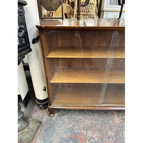 211 - A mid 20th century walnut bookcase with two glass sliding doors - approx. 85cm high x 99cm wide x 28... 