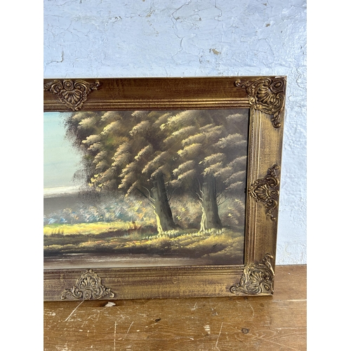 271 - A gilt framed oil on canvas of a woodland scene, signed lower right - approx. 51cm high x 90cm wide