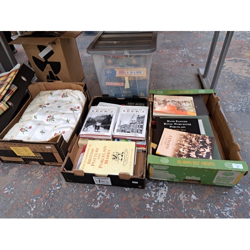 843 - Seven boxes containing glassware, linen material, table lamps, local interest books etc.