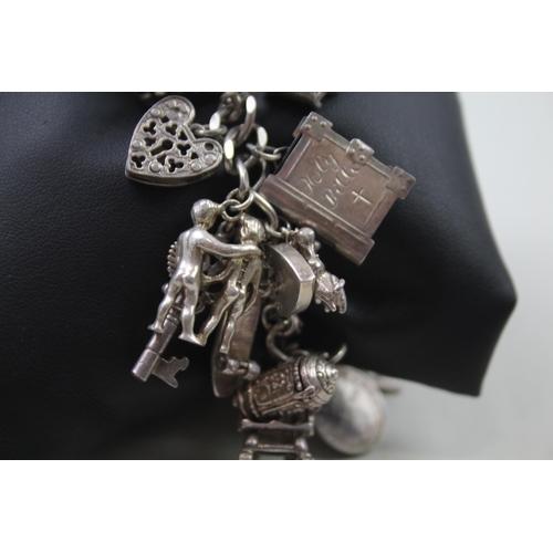 2442 - A silver charm bracelet with assorted charms - approx. gross weight 87g