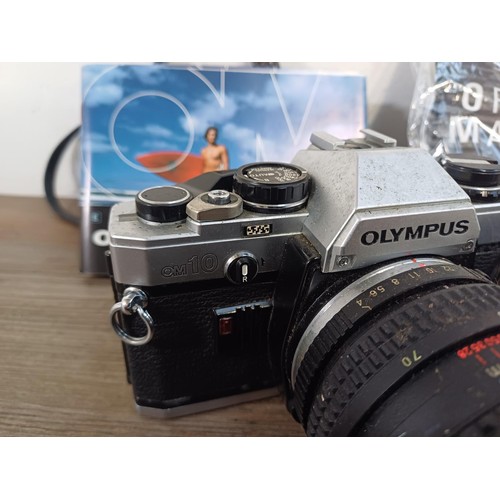 605 - A collection of Olympus items to include two OM10 35mm SLR cameras, nine cased T20 flashes, two OM W... 