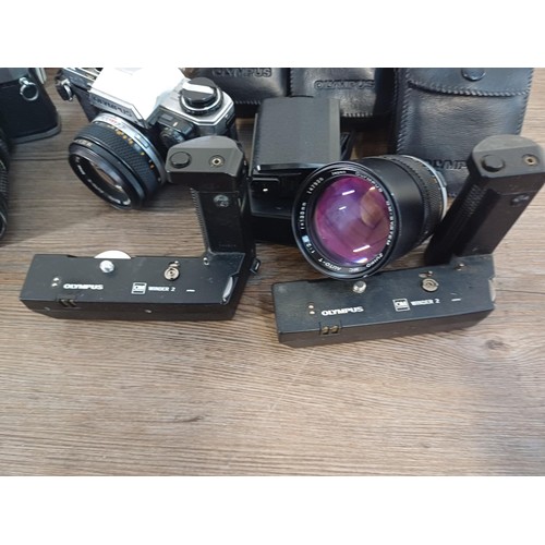 605 - A collection of Olympus items to include two OM10 35mm SLR cameras, nine cased T20 flashes, two OM W... 