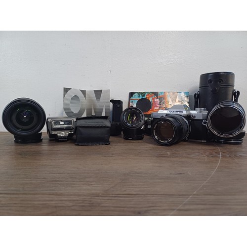 605A - A collection of Olympus items, OM30 35mm SLR camera fitted with Zuiko 135mm 1:3.5 lens, Zuiko 50mm 1... 