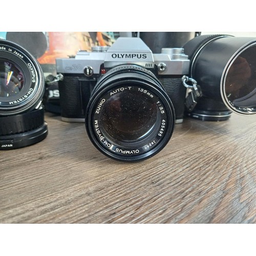 605A - A collection of Olympus items, OM30 35mm SLR camera fitted with Zuiko 135mm 1:3.5 lens, Zuiko 50mm 1... 