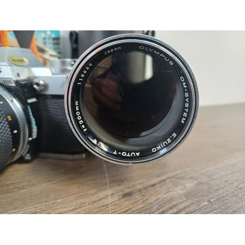 605A - A collection of Olympus items, OM30 35mm SLR camera fitted with Zuiko 135mm 1:3.5 lens, Zuiko 50mm 1... 