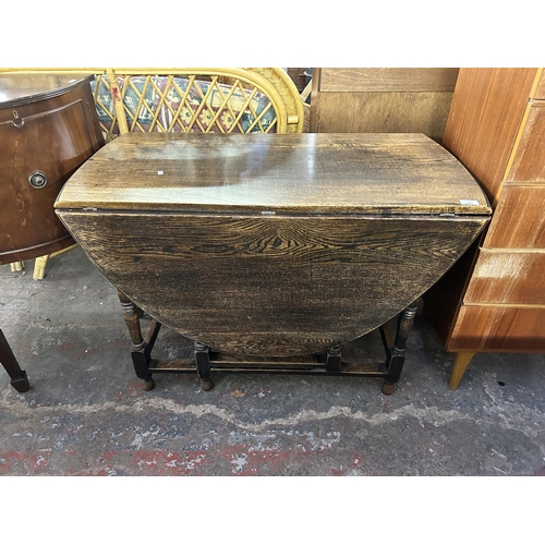 187 - An early 20th century oak drop leaf gate leg oval dining table