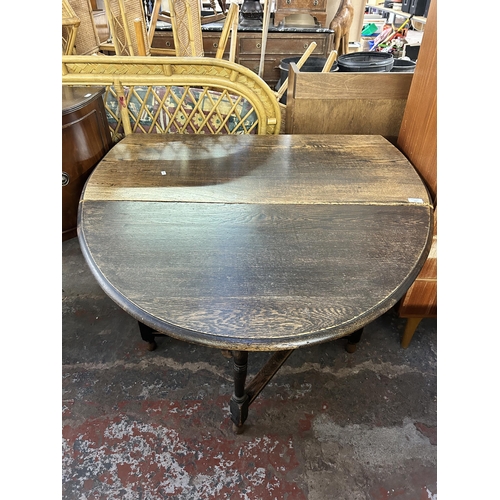 187 - An early 20th century oak drop leaf gate leg oval dining table