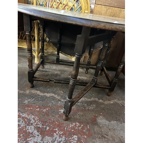 187 - An early 20th century oak drop leaf gate leg oval dining table