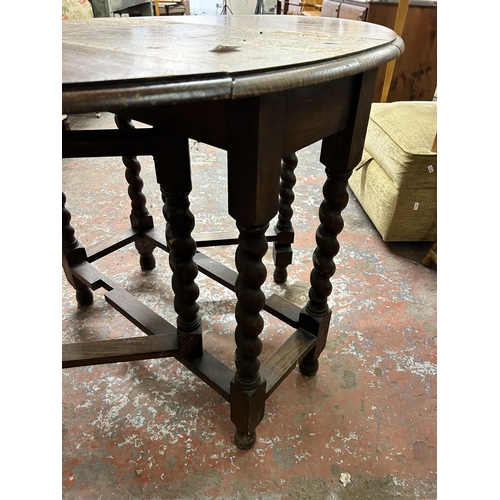 224 - An early 20th century oak drop leaf gate leg dining table on barley twist supports