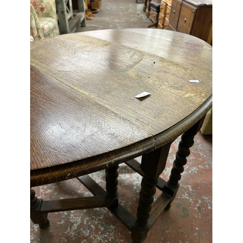 224 - An early 20th century oak drop leaf gate leg dining table on barley twist supports