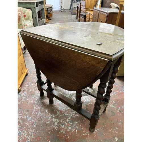 224 - An early 20th century oak drop leaf gate leg dining table on barley twist supports