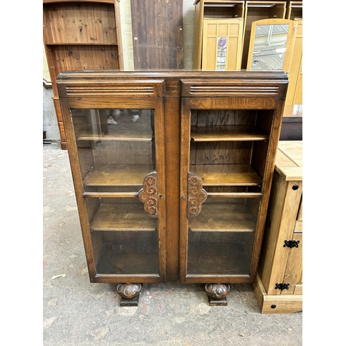 52A - A 1930s carved oak bookcase with two glazed doors - approx. 120cm high x 91cm wide x 30cm deep