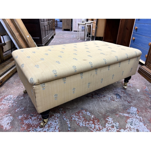 81 - A Victorian style fabric upholstered storage footstool with ebonised supports and brass castors - ap... 