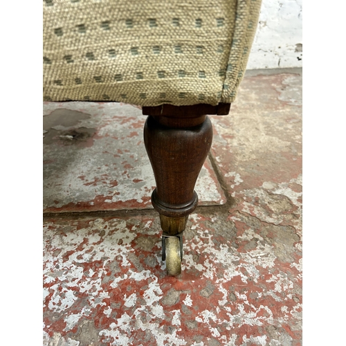 82 - A Victorian fabric upholstered button back armchair with rosewood supports and brass castors - appro... 