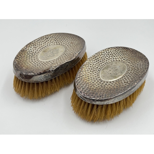 2302 - An Edwardian leather cased pair of William Hair Haseler hallmarked Birmingham silver clothes brushes... 