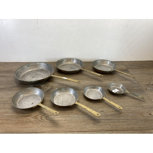 402 - A set of seven 19th century style graduating brass frying pans - largest approx. 23.5cm diameter