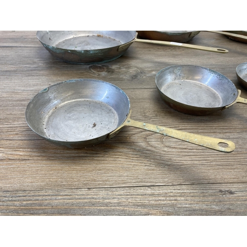 402 - A set of seven 19th century style graduating brass frying pans - largest approx. 23.5cm diameter