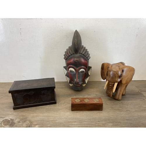 560 - A collection of carved treen items to include African tribal style wall masks, carved elephants, car... 