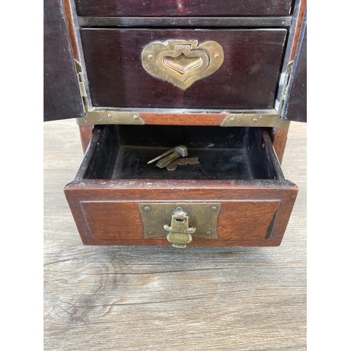 562 - A vintage Chinese hardwood miniature three door cabinet with brass details and original lock and key... 