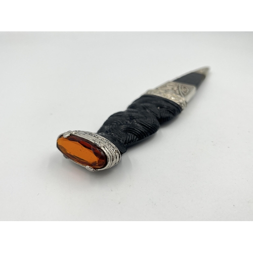 2319 - A J. Nowill & Sons Ltd. Skean-DHU dagger with sheath, carved handle and amber glass and white metal ... 