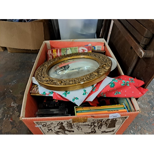 1023 - A box containing gilt framed convex wall mirror, toys, magazines etc.