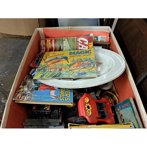 1023 - A box containing gilt framed convex wall mirror, toys, magazines etc.