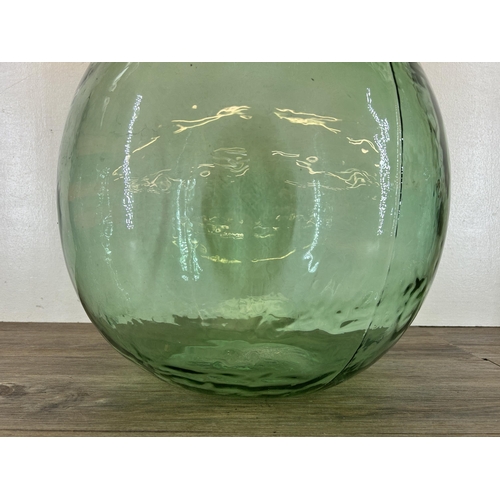 382 - A mid 20th century green glass carboy - approx. 65cm high