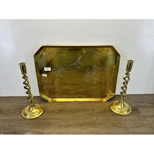 426 - Three pieces of brassware, two barley twist candle sticks - approx. 31cm high and one engraved tray ... 