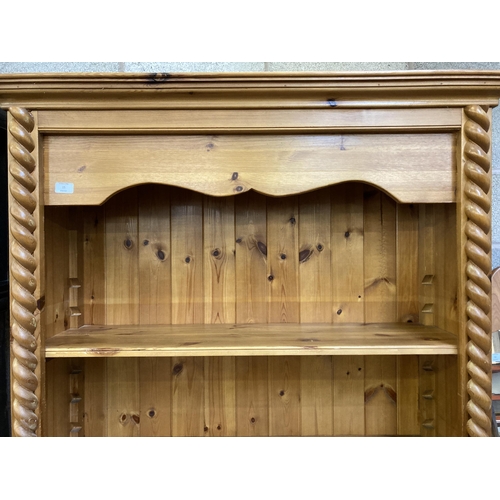 15 - A modern pine three tier open bookcase with two lower cupboard doors and barley twist design - appro... 
