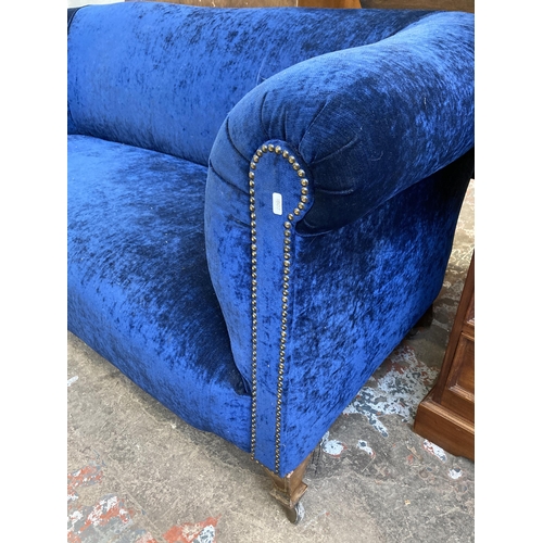 42 - A Victorian blue fabric upholstered two seater sofa on inlaid mahogany supports and later added cast... 