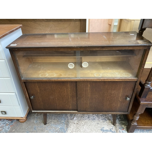 53 - A mid 20th century oak veneer display cabinet with two glass sliding doors