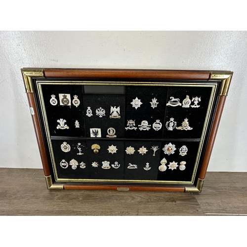 2232D - Three mahogany and gilt metal framed collections of military cap badges