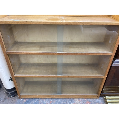 212 - A mid 20th century oak three tier bookcase with six glass sliding doors