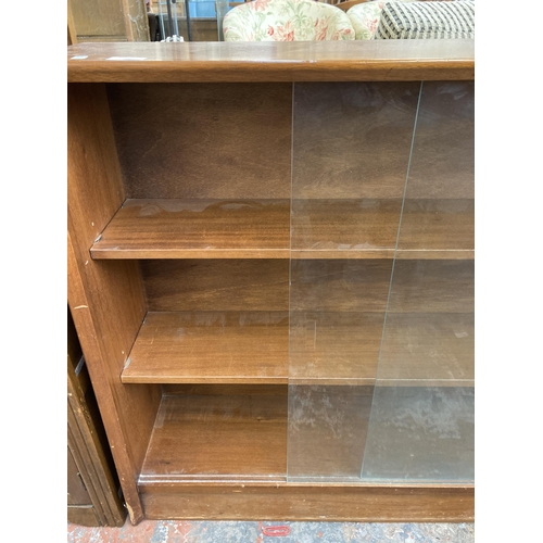 215 - A mid 20th century Herbert E. Gibbs teak three tier bookcase with two glass sliding doors - approx. ... 