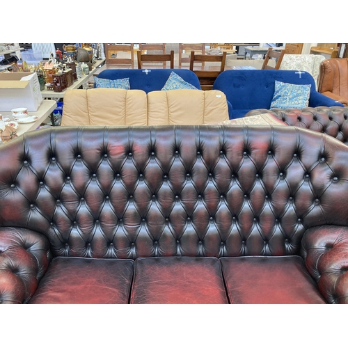 223 - An oxblood leather Chesterfield wingback three seater sofa